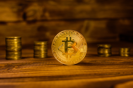 Bitcoin and stack of coins on rustic wooden tableの写真素材