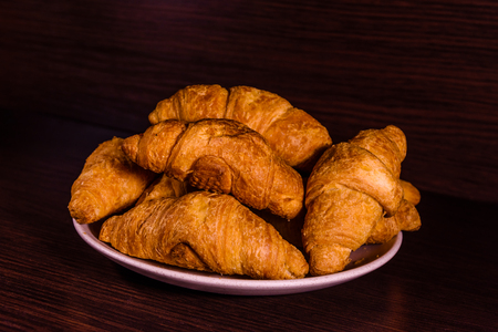 Plate with fresh croissants on dark wooden tableの写真素材