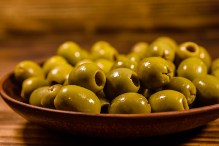 Ceramic plate with green olives on rustic wooden tableの写真素材