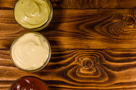 Different sauces in glass bowls on rustic wooden table. Top viewの写真素材
