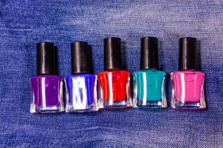 Different nail polishes on blue jeans. Top viewの写真素材