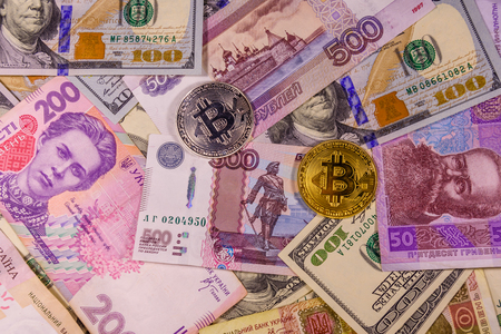 Bitcoin coins on american, ukrainian and russian banknotesの写真素材