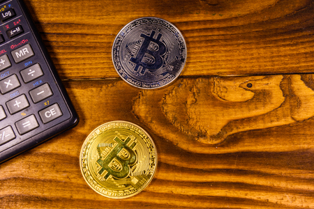 Bitcoins and scientific calculator on rustic wooden table. Top viewの写真素材