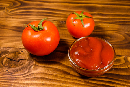 Ripe tomatoes and ketchup on rustic wooden tableの写真素材