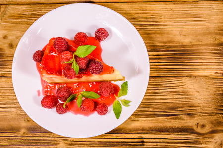White plate with cheesecake New York, leaves of mint and raspberries on rustic wooden table. Top viewの写真素材