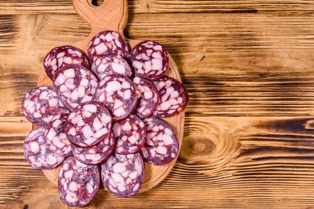 Cutting board with sliced salami sausage on rustic wooden table. Top viewの写真素材