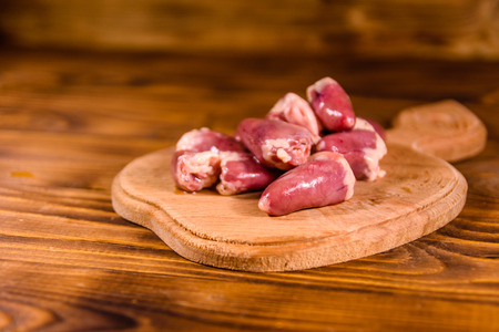 Cutting board with raw chicken hearts on rustic wooden tableの写真素材