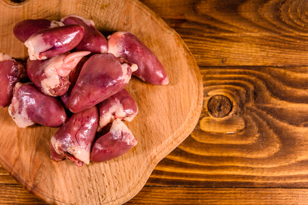 Cutting board with raw chicken hearts on rustic wooden table. Top viewの写真素材