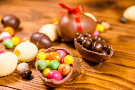 Chocolate easter eggs and multicolored candies on rustic wooden tableの写真素材