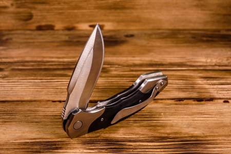Opened folding knife on rustic wooden tableの写真素材