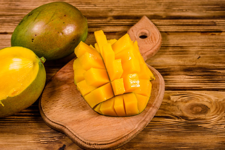 Cutting board with chopped mango fruit on rustic wooden tableの写真素材