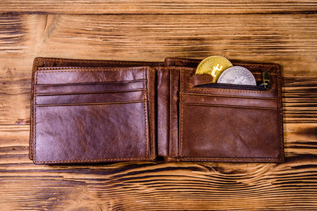 Brown leather wallet and bitcoins on wooden background. Top viewの写真素材