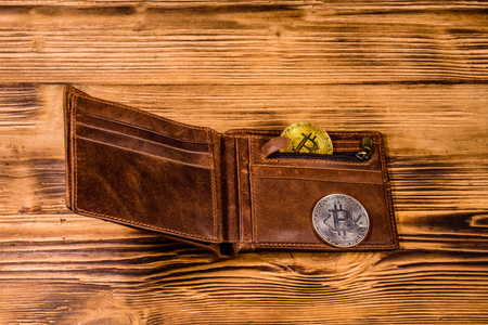 Brown leather wallet and bitcoins on wooden backgroundの写真素材