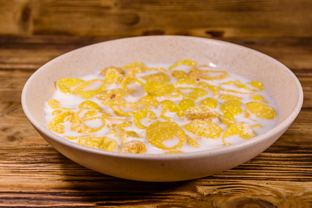 Ceramic plate with cornflakes and milk on wooden table. Healthy eatingの写真素材