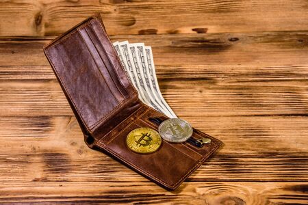 Brown leather wallet, bitcoins and one hundred dollar banknotes on wooden backgroundの写真素材