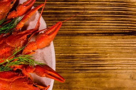 Plate with boiled crayfishes on rustic wooden table. Top viewの写真素材