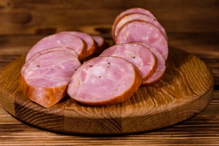 Cutting board with sliced sausage on rustic wooden tableの写真素材