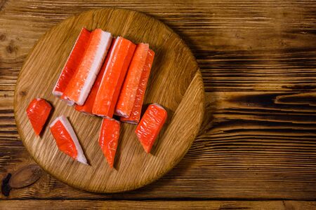 Cutting board with pile of crab sticks on wooden table. Top viewの写真素材