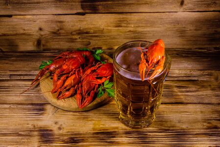 Glass of beer and boiled crayfish on rustic wooden tableの写真素材
