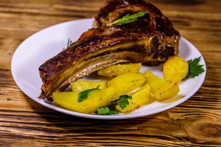 Plate with roasted ribeye steak and potatoes on rustic wooden tableの写真素材
