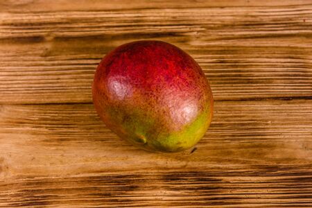 Whole red mango fruit on rustic wooden tableの写真素材
