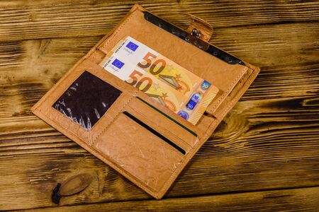 Brown leather wallet with fifty euro banknotes on wooden backgroundの写真素材
