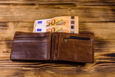 Brown leather wallet with fifty euro banknotes on wooden backgroundの写真素材