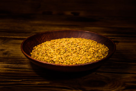 Ceramic plate with fenugreek seeds on rustic wooden table