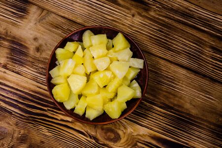 Ceramic plate with chopped canned pineapple on rustic wooden table. Top viewの写真素材