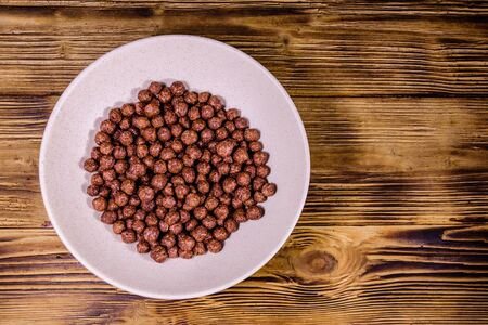 Ceramic plate with chocolate cereal balls on rustic wooden table. Top viewの写真素材