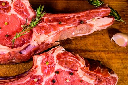 Raw ribeye steak, spices, rosemary and garlic on wooden cutting board. Top viewの写真素材