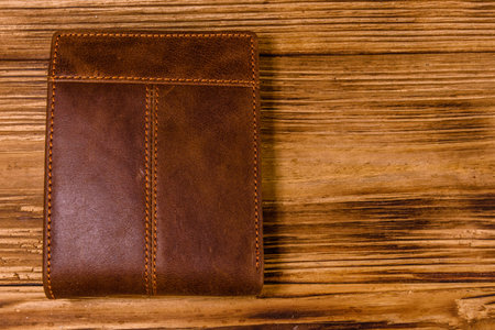 Closed brown leather wallet on rustic wooden table. Top viewの写真素材