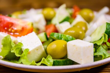 Ceramic plate with greek salad on rustic wooden tableの写真素材
