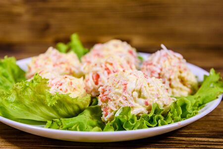 White plate with crab-cheese balls and lettuce leaves on rustic wooden tableの写真素材