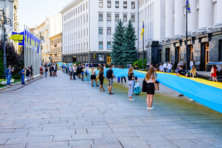 Kiev, Ukraine - August 23, 2019: People with a huge ukrainian flag near administration of president of Ukraine during celebration of Day of State Flag of Ukraineのeditorial素材