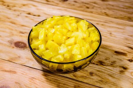 Glass bowl with chopped pineapple on rustic wooden tableの写真素材