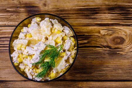 Festive salad with chicken breast, canned pineapple, cheese, sweet corn and mayonnaise on rustic wooden table. Top viewの写真素材