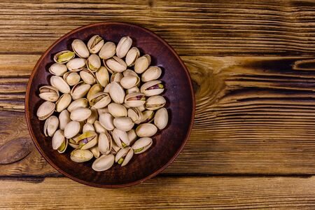 Ceramic plate with pistachio nuts on wooden table. Top viewの写真素材