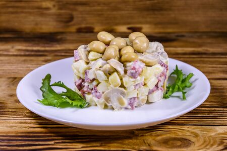 Salad with marinated mushrooms, sausage, onion, boiled potato and mayonnaise on wooden tableの写真素材