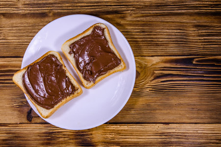 Two sandwiches with chocolate spread on white plate. Top view
