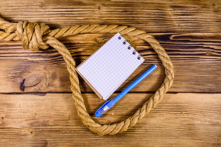 Rope with noose for suicide, blank notepad and pen on wooden backgroundの写真素材
