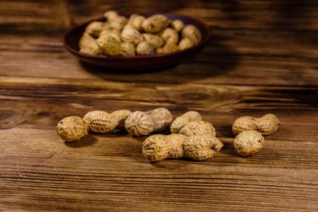 Heap of unpeeled peanuts on rustic wooden table