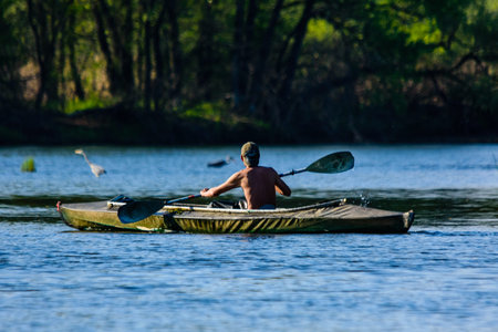 Young man kayaking on river at summer