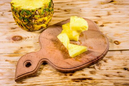 Cutting board with sliced pineapple on rustic wooden tableの写真素材