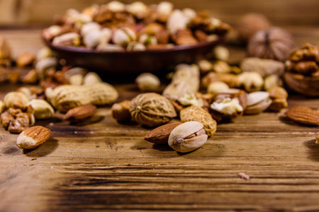 Various nuts (almond, cashew, hazelnut, pistachio, walnut) in ceramic plate on wooden table. Vegetarian meal. Healthy eating conceptの写真素材