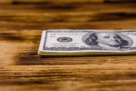 Stack of one hundred dollar banknotes on wooden background