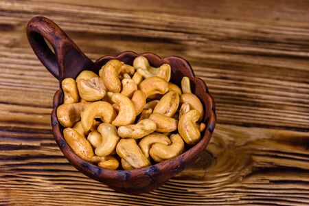 Ceramic bowl with roasted cashew nuts on wooden tableの写真素材