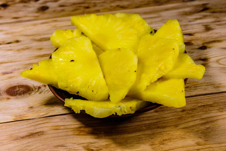 Ceramic plate with sliced pineapple on rustic wooden table