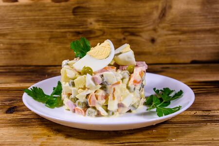 Ceramic plate with russian traditional new year salad olivier on wooden tableの写真素材