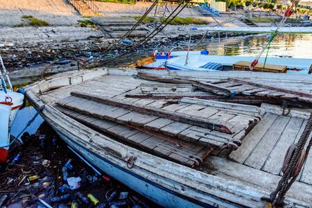Old boats moored in dirty harbour. Pollution of river, sea, ocean water with plastics and other garbage. Environmental pollution conceptの写真素材